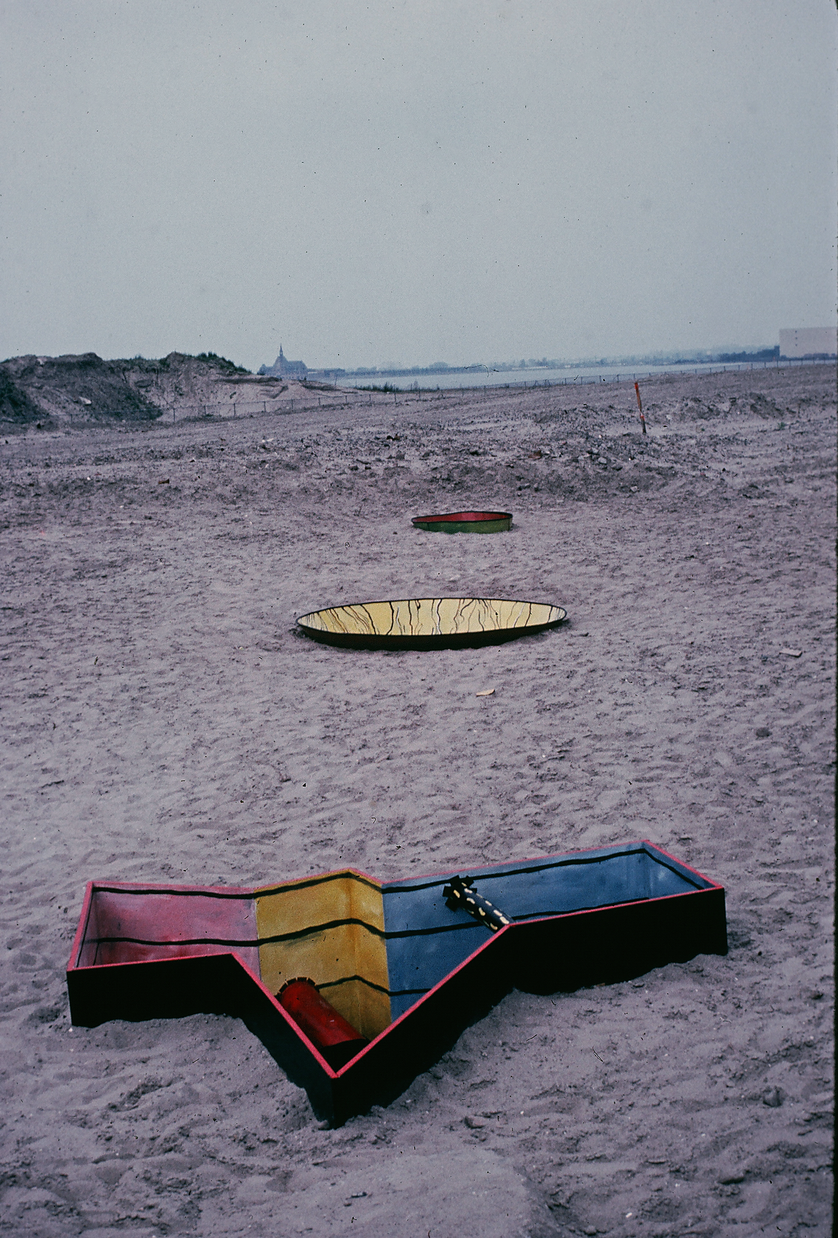 3 of 5 sculptures embedded in sand. made of painted plywood and sheet metal.