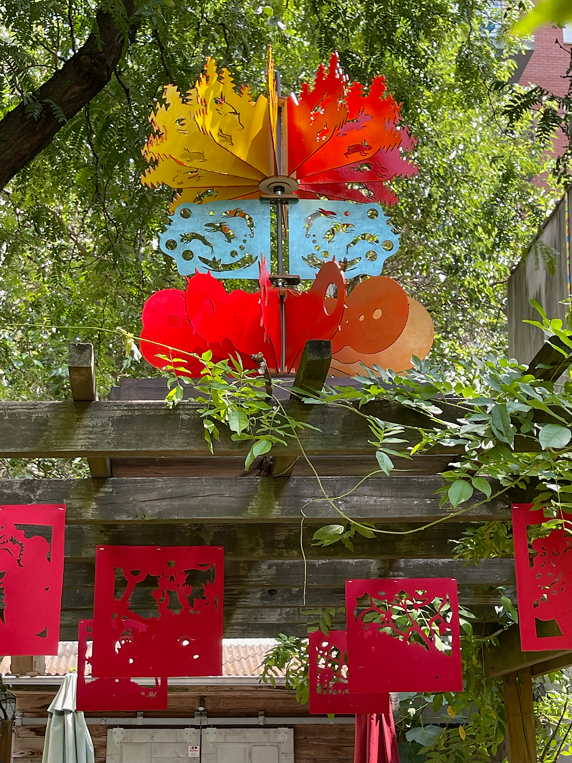 3 tiered weathervane and fabric flags attached to trellis in garden.